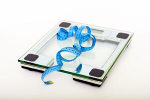 Balança digital de vidro com fita métrica azul ao lado